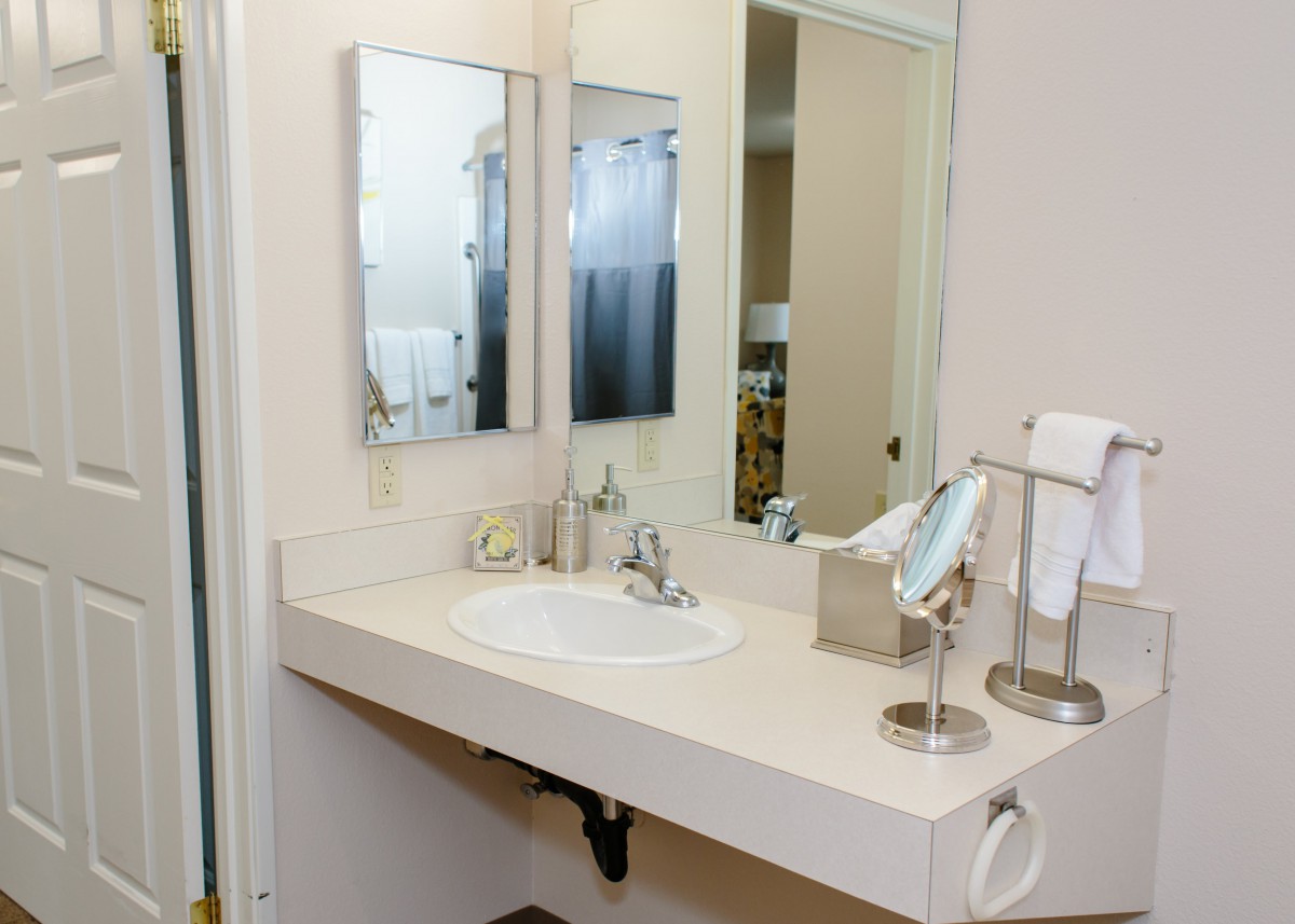 A clean and tidy bathroom with a wide countertop and mirror.