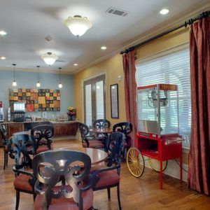 An indoor dining area featuring a popcorn machine, tables, and chairs.