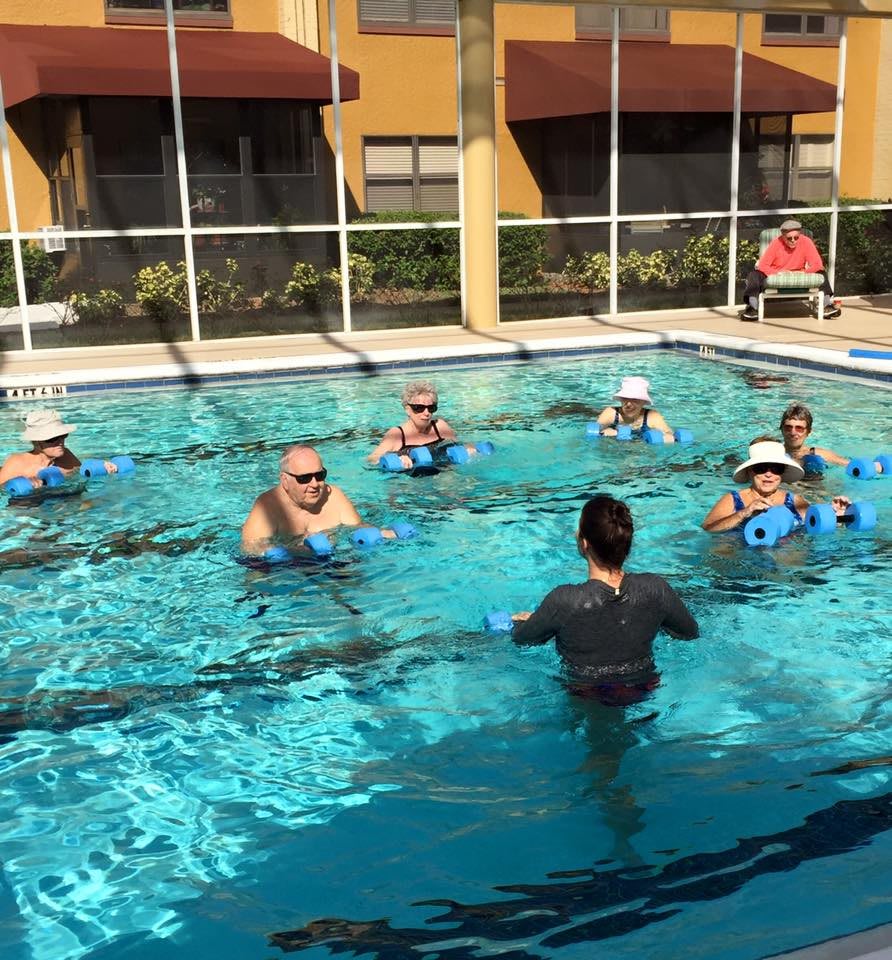A group of people participating in a water aerobics class in an outdoor pool.