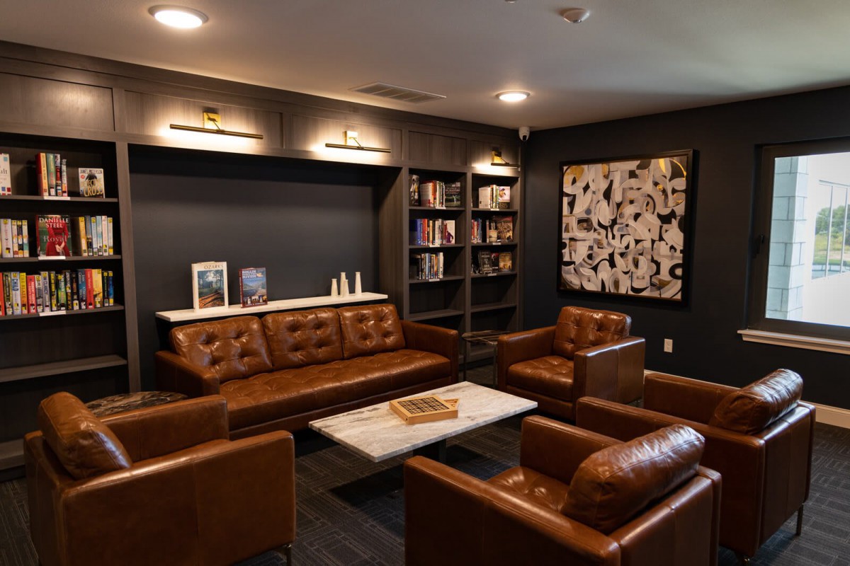 A cozy lounge with leather seating and a stylish bookshelf.