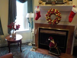 A cozy living room decorated for Christmas with a festive wreath and stockings hanging by the fireplace.