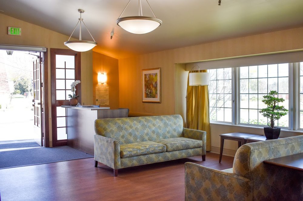 A cozy living room with a sofa, table, and large windows.