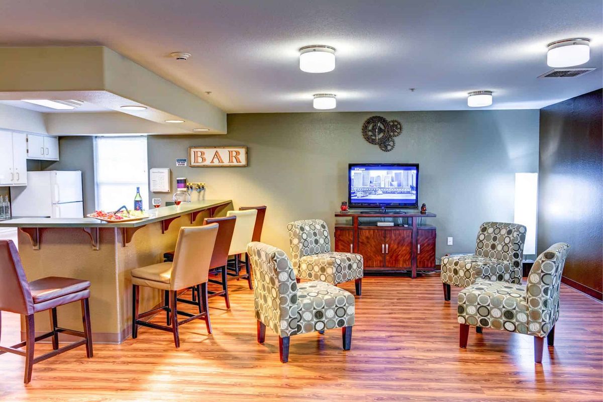 A cozy lounge area featuring a bar, comfortable seating, and a television.
