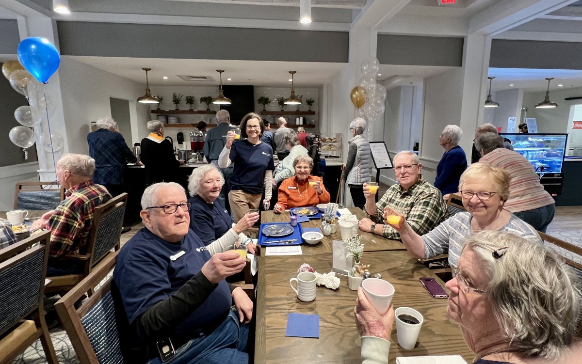 A group of seniors enjoying a social gathering with drinks and smiles.