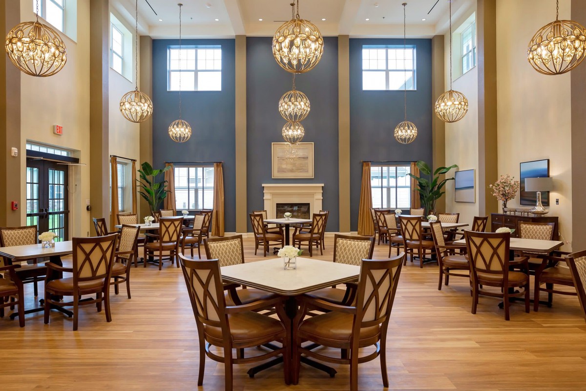 A well-decorated dining room with chandeliers, tables, and a fireplace.