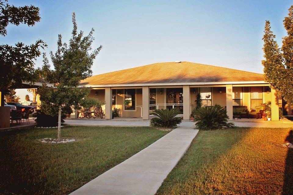 A suburban house with a walkway leading to the entrance, surrounded by a grassy yard.
