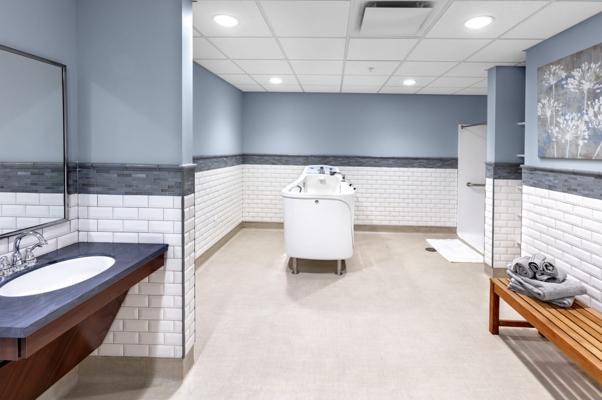 A modern locker room with a central white bathtub and tiled walls.