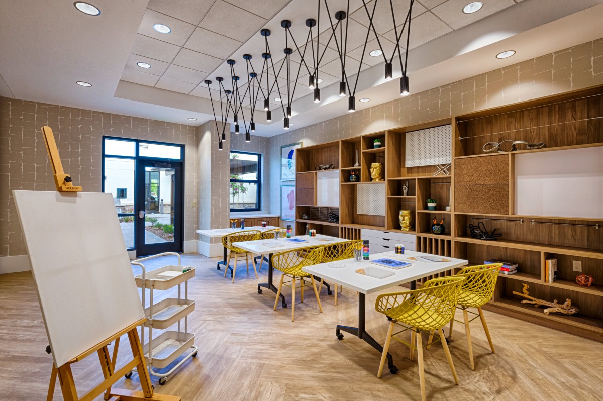 A modern study area with contemporary design elements, featuring tables, chairs, and elegant chandeliers.