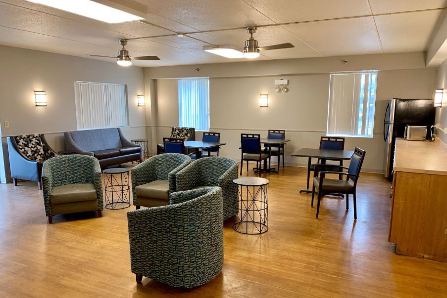 A cozy lounge area with various chairs, tables, and large windows.