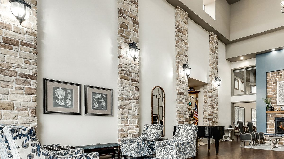 A modern living room featuring stone wall accents, high ceilings, and contemporary furniture.