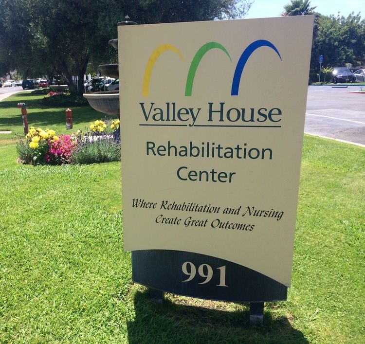 Sign for the Valley House Rehabilitation Center located outdoors with landscaping.