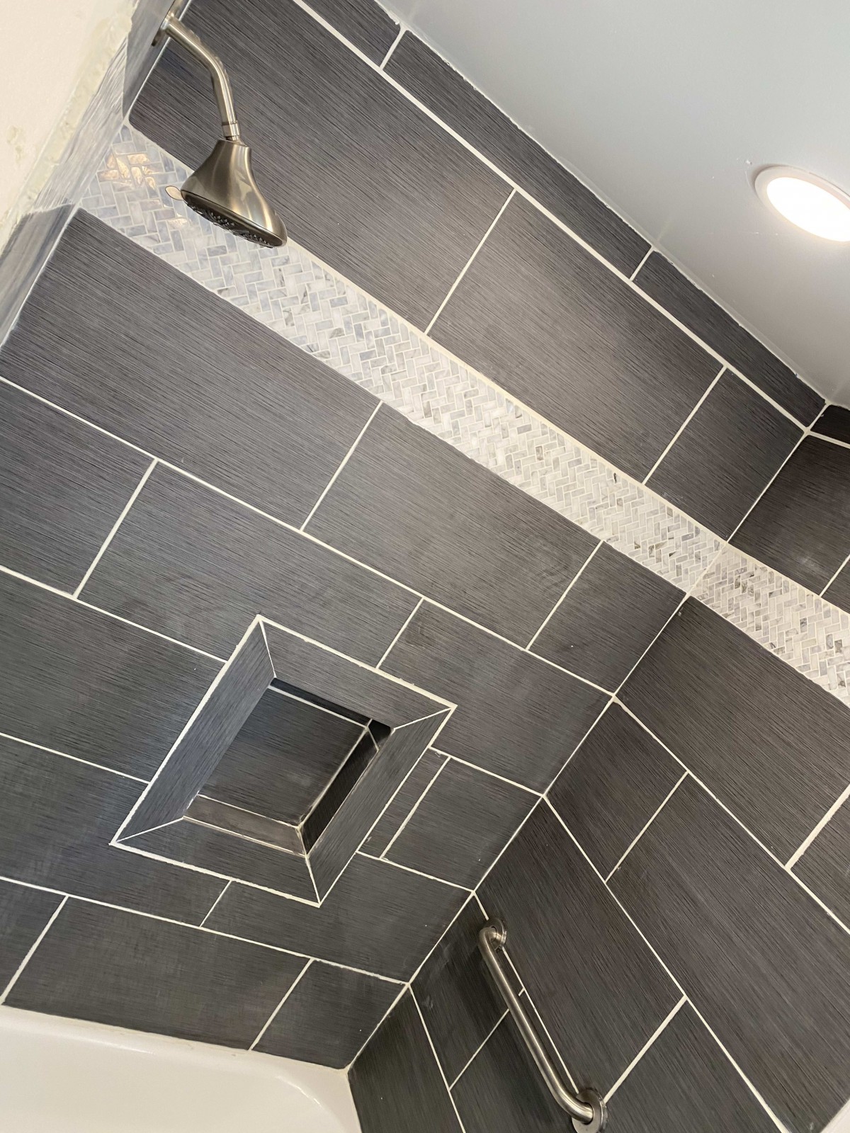 Modern bathroom shower with dark tiles and accent stripe.