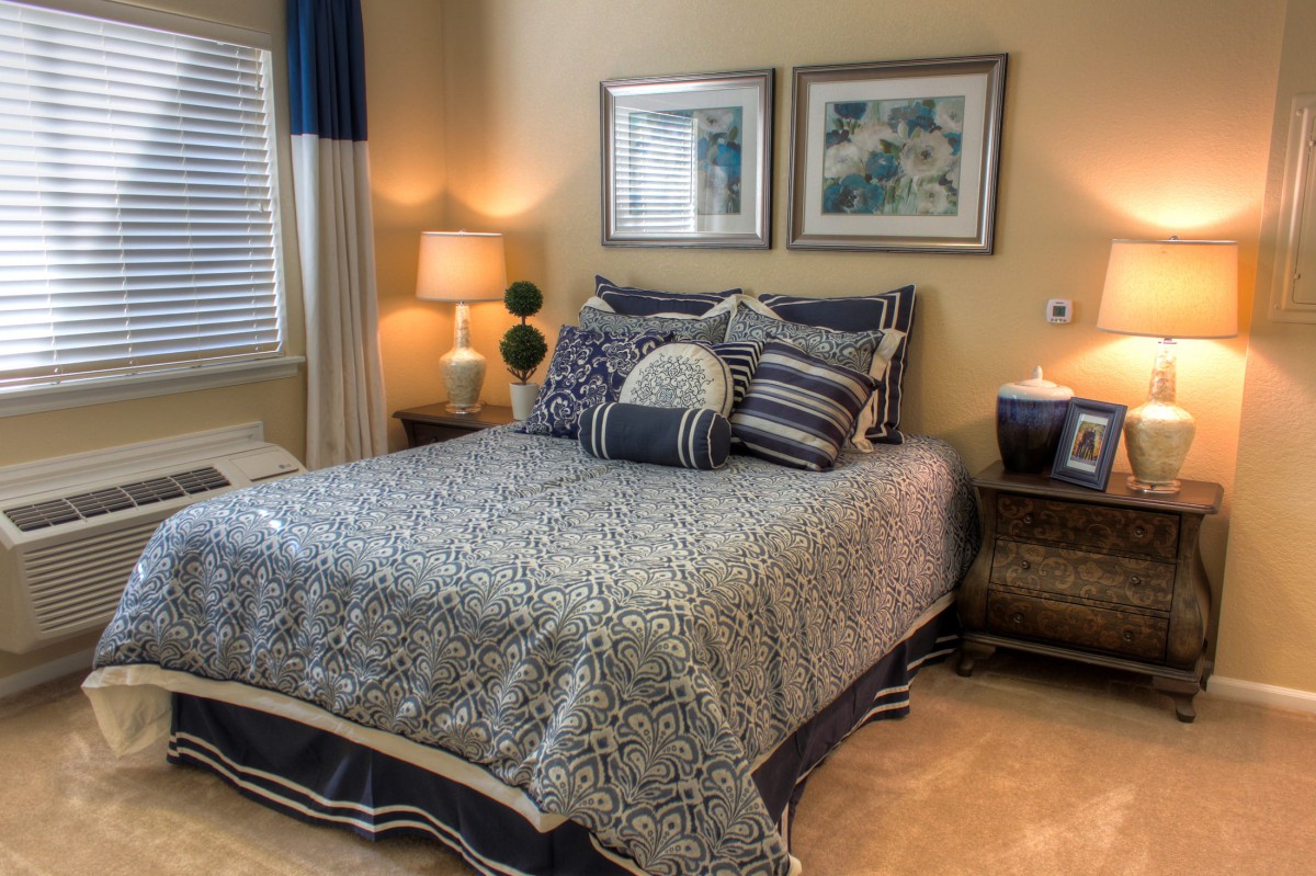 A cozy bedroom with a neatly made bed, decorative pillows, and ambient lighting.