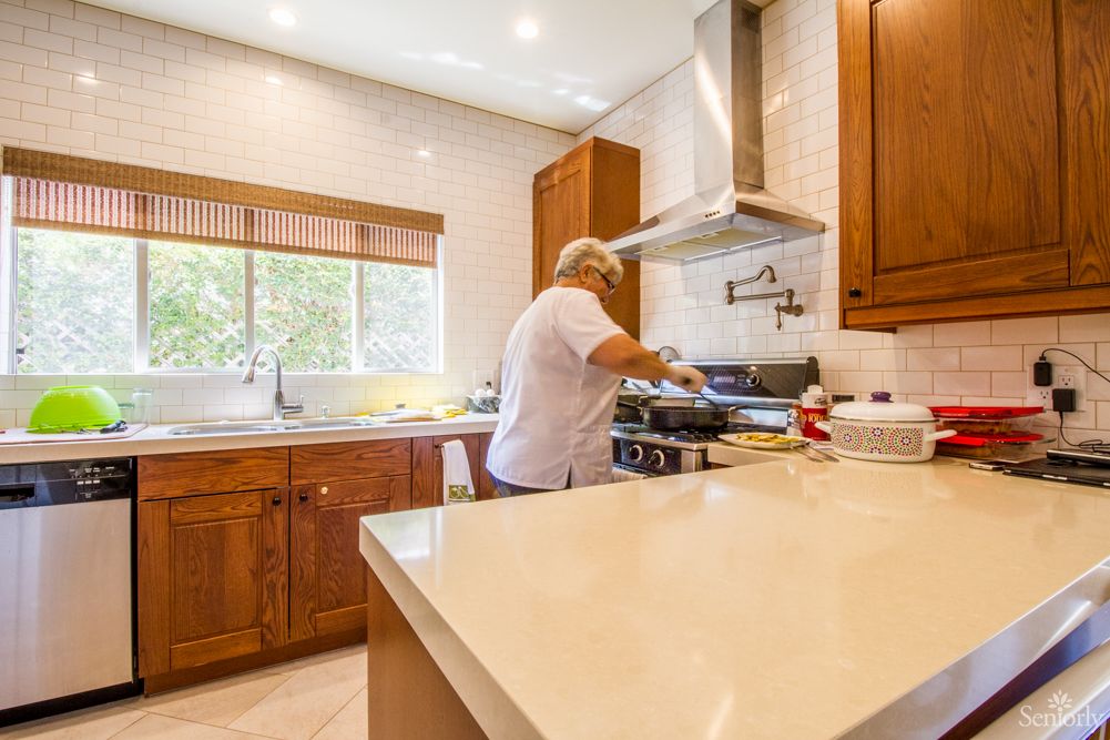 A person cooking in a modern kitchen with wooden cabinets.