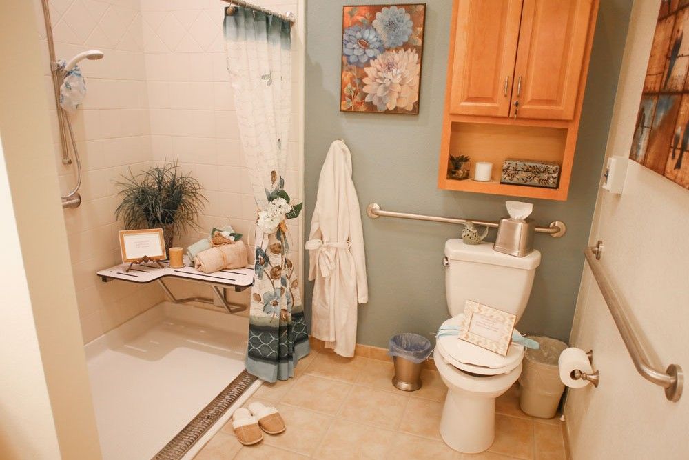 A cozy bathroom featuring a shower, toilet, and artfully decorated with plants and wall art.