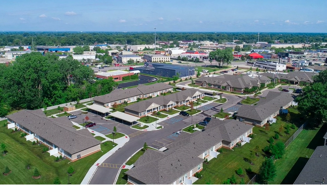 Aerial view of a suburban residential area with houses, streets, and surrounding greenery.
