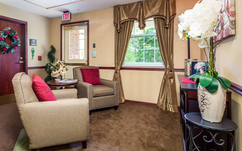 A cozy living room with beige armchairs, gold curtains, and decorative plants.