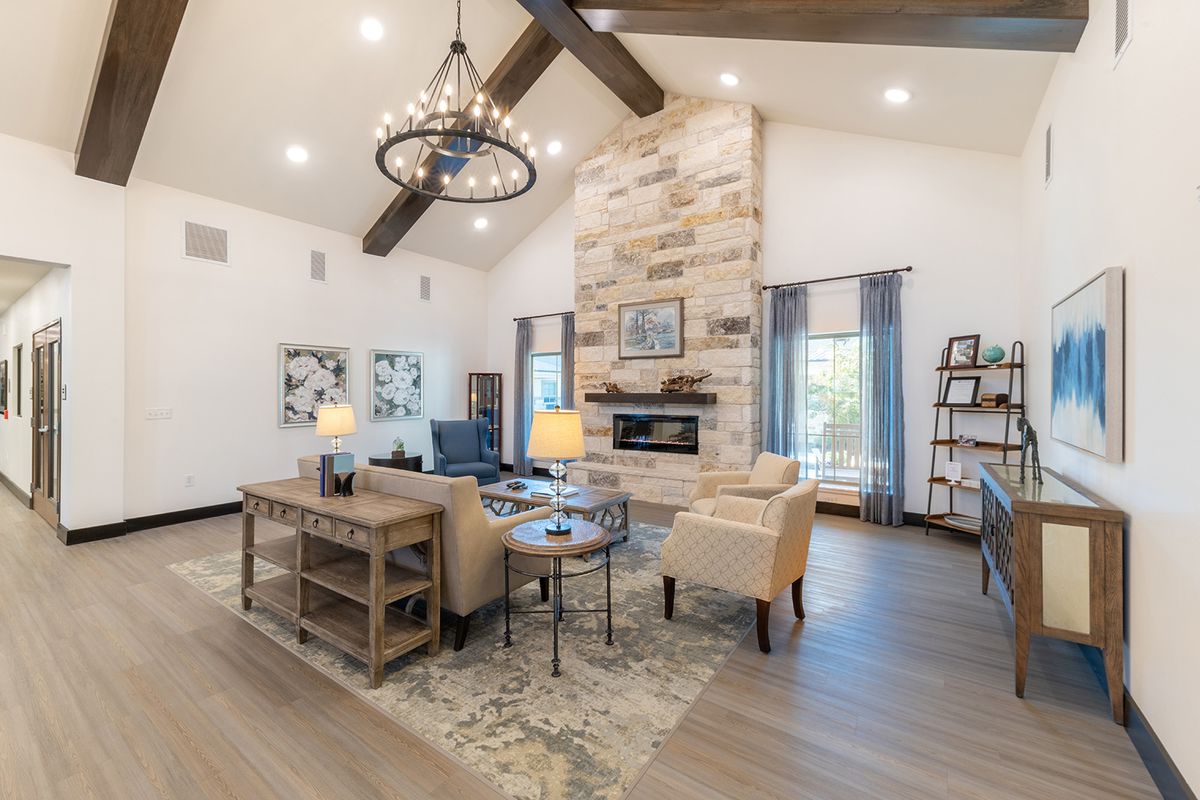 A modern living room featuring a vaulted ceiling, contemporary furnishings, and a stone fireplace with wood flooring.