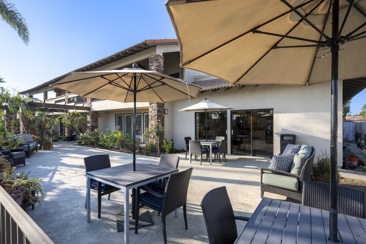 A modern patio with tables, chairs, and umbrellas on a sunny day.