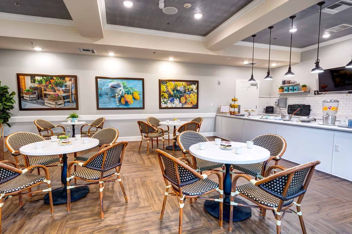A cozy cafe interior with elegant tables and chairs, adorned with vibrant artwork on the walls.