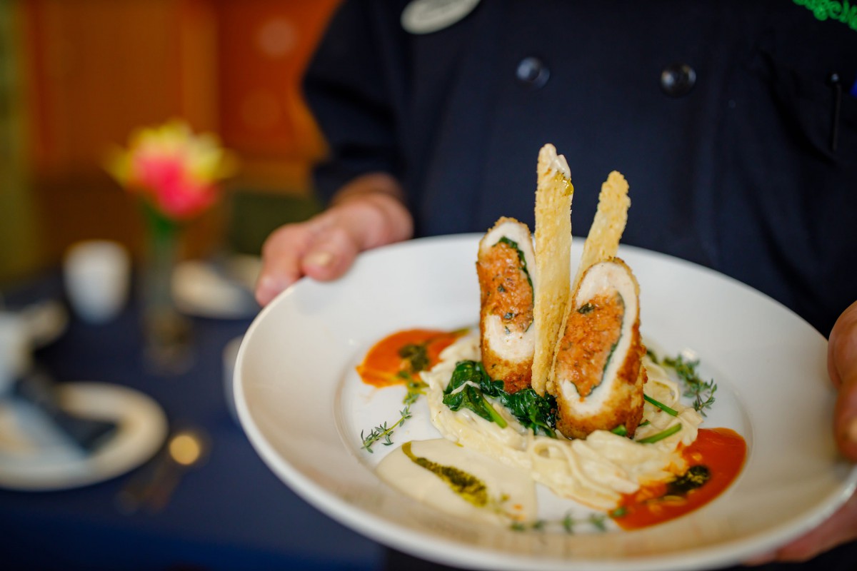 A beautifully plated gourmet dish being presented by a chef.
