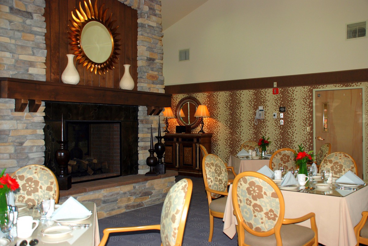 A cozy dining room with a fireplace, elegantly set tables, and decorative elements.