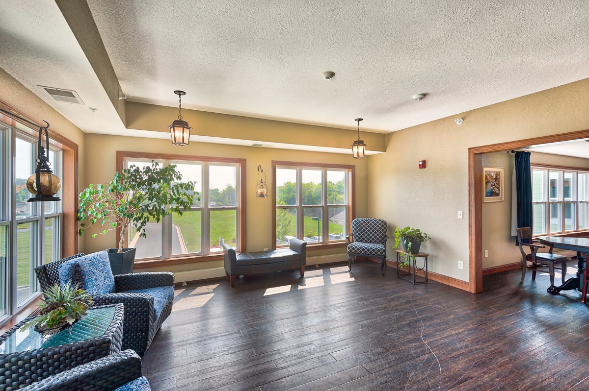 A cozy living room with large windows, comfortable seating, and wooden flooring.
