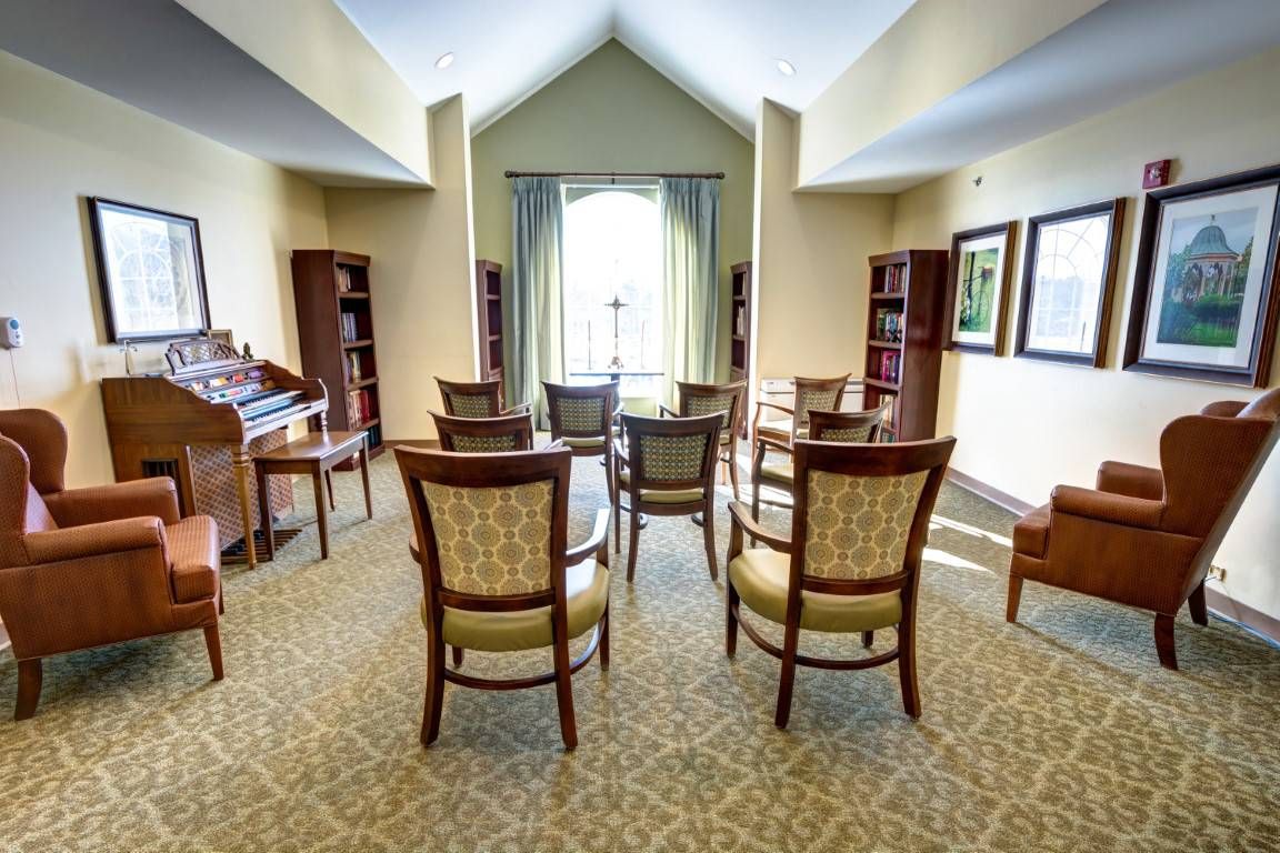 A well-appointed meeting room with several chairs arranged in rows, featuring bookshelves and a carpeted floor.