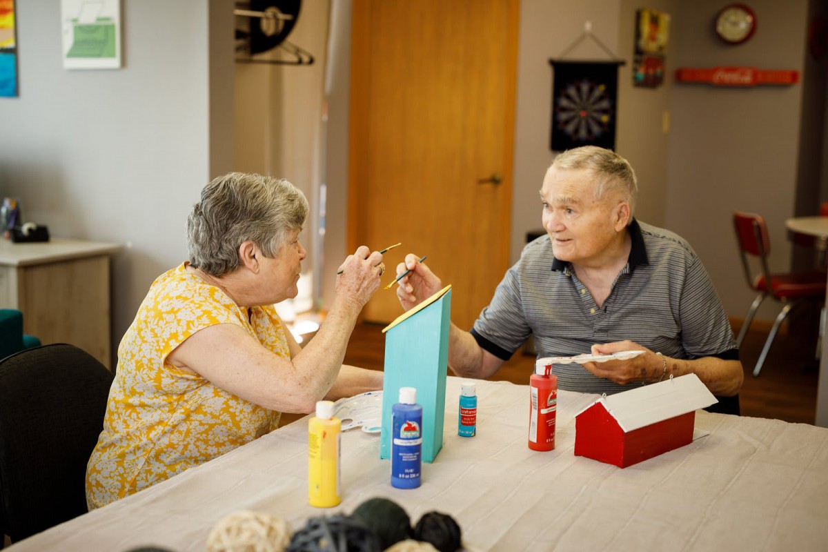 An elderly couple engaged in a fun painting activity together.