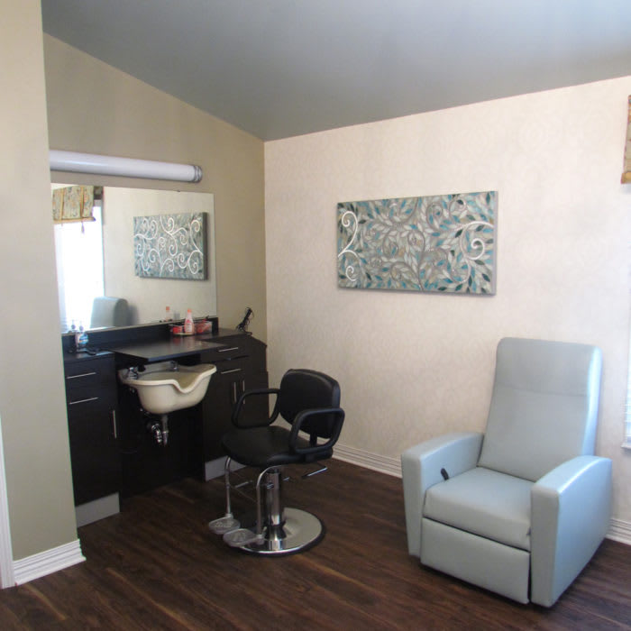 A cozy salon interior with a styling chair, washing station, and comfortable seating.