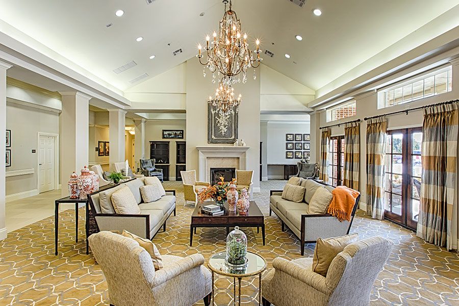 A luxurious living room featuring a grand chandelier, comfortable seating area, and an elegant fireplace.