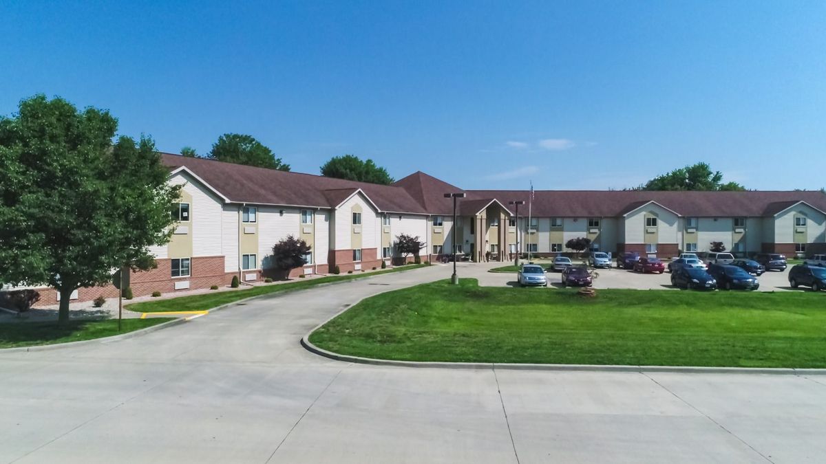 A residential building with a driveway and well-maintained lawn under a clear blue sky.