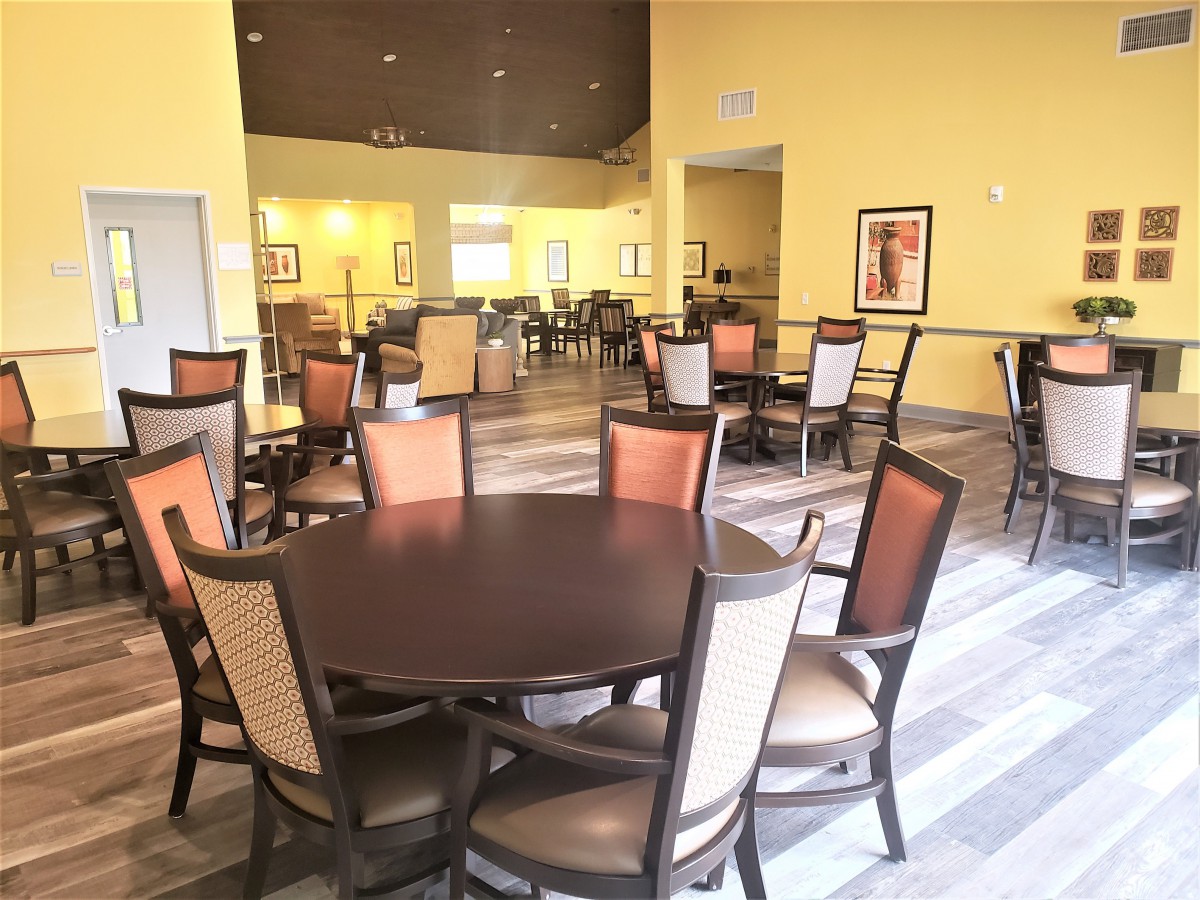 A spacious dining area with multiple tables and chairs, featuring a warm color palette.
