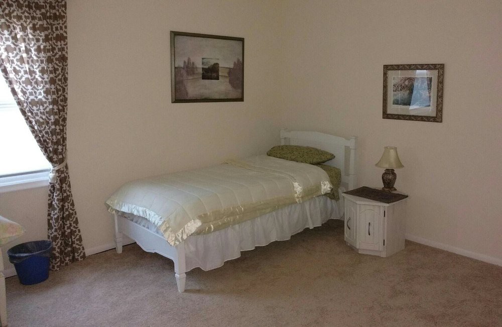 A simple bedroom with a single bed and nightstand.