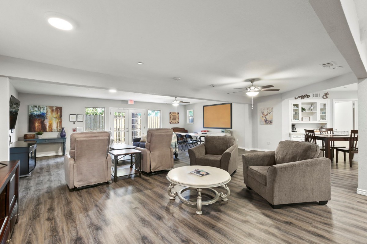 A spacious living room featuring comfortable armchairs, a round coffee table, and modern wood flooring.