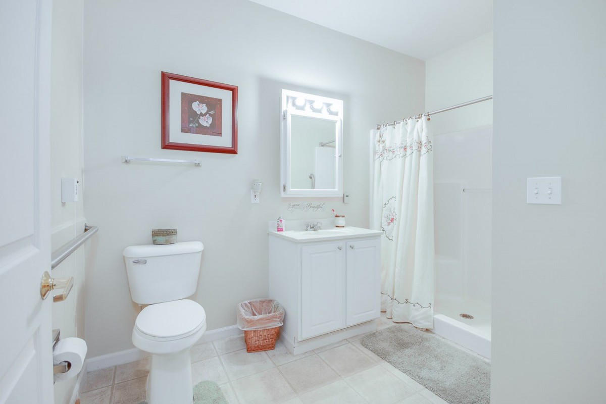 A minimalist bathroom featuring a white sink, toilet, and shower with simple decor.