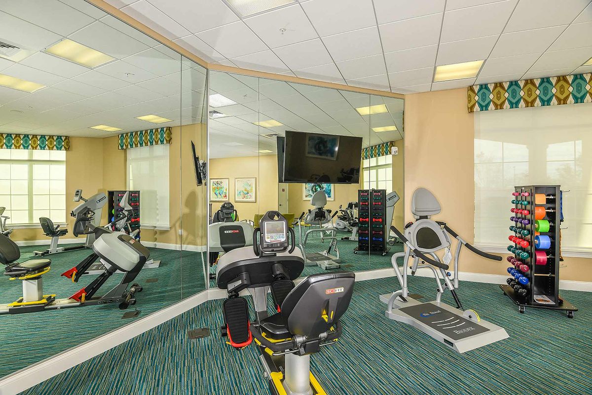A well-equipped gym with mirrors and stationary bikes.