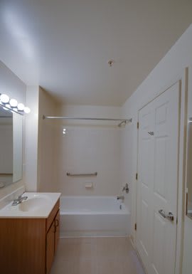 A clean and simple bathroom featuring a bathtub, sink with a mirror, and modern light fixtures.