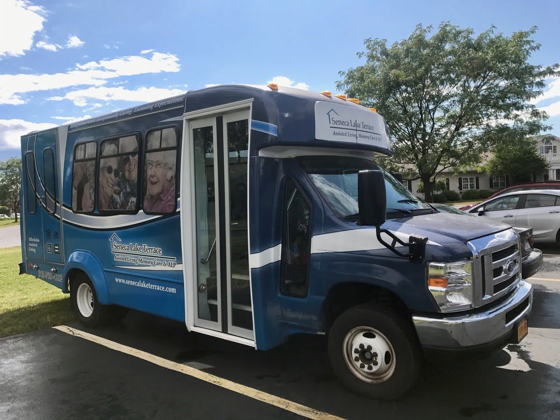 A blue shuttle bus parked in a lot under a clear sky.