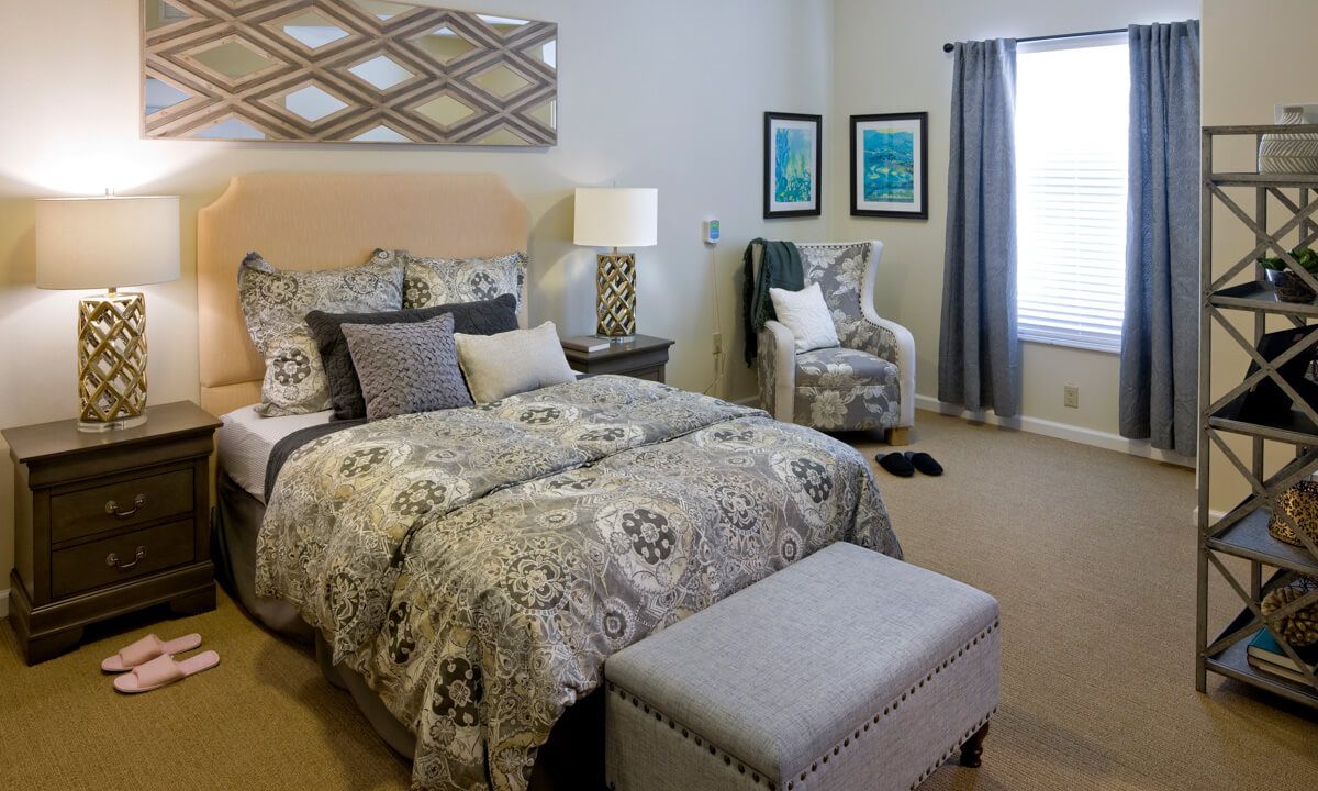A cozy bedroom featuring a patterned bedspread, decorative pillows, and elegant lighting.
