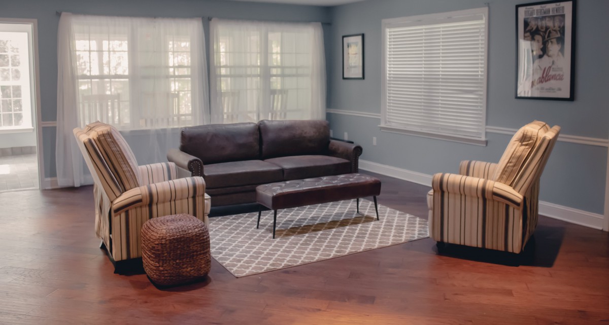A cozy living room with a modern sofa, striped armchairs, and a patterned rug.