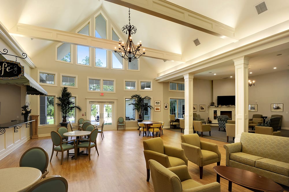 A spacious and elegantly designed living room featuring a high ceiling, chandelier, and ample seating.