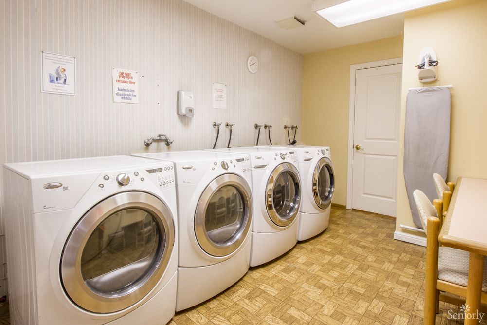 A neatly arranged laundry room with several front-loading washing machines.