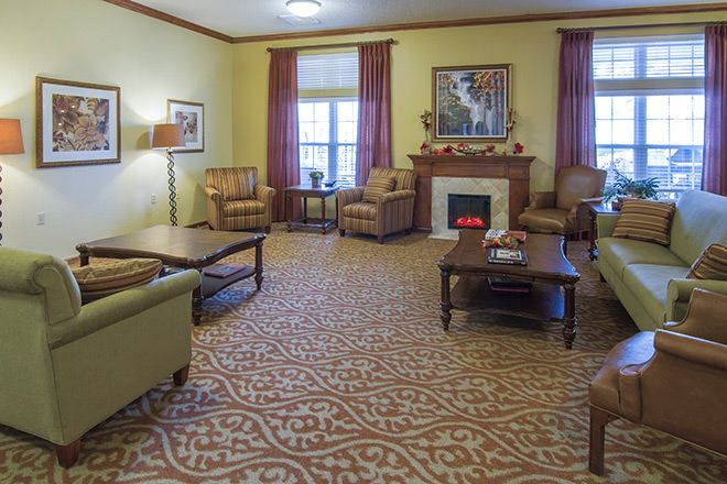 A cozy living room with a fireplace, sofas, and armchairs arranged around a coffee table.