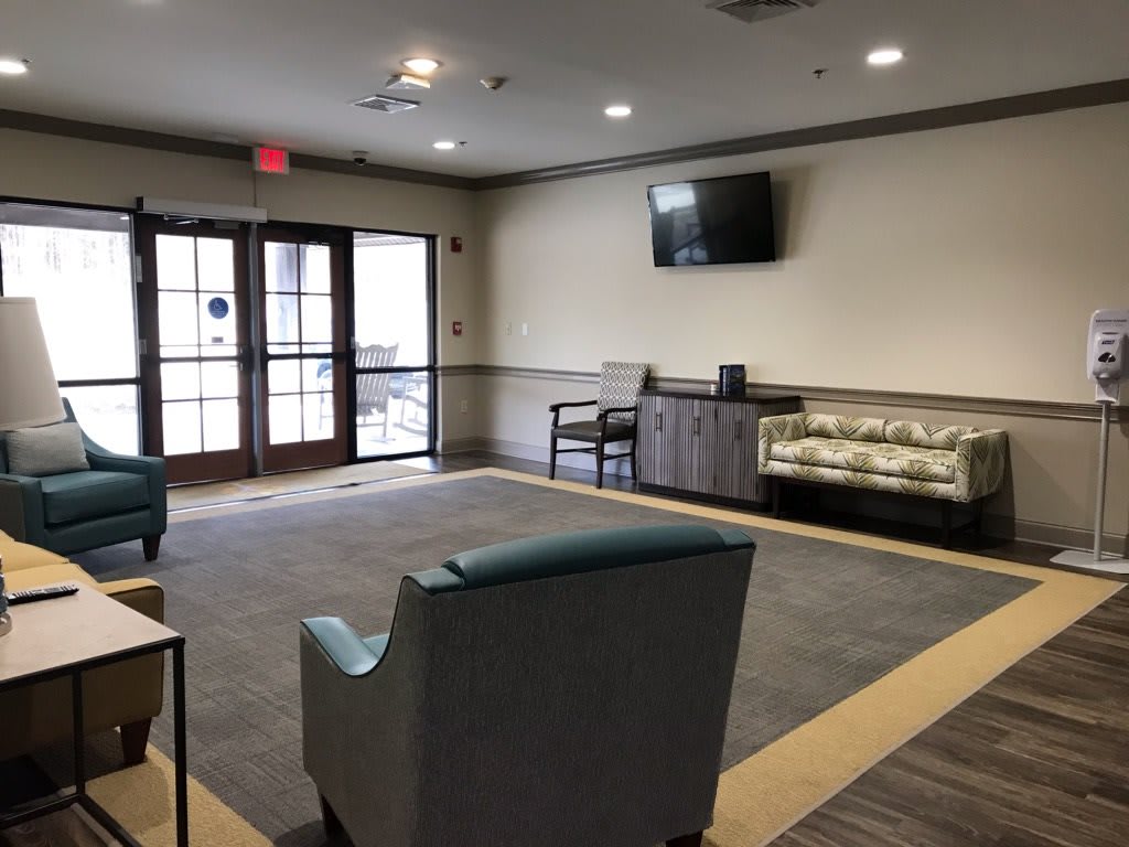 A modern waiting room with comfortable seating and a wall-mounted television.