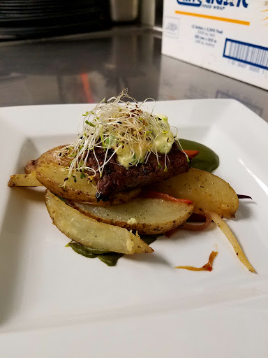 A beautifully plated gourmet dish featuring seasoned meat atop roasted potatoes, garnished with fresh sprouts.