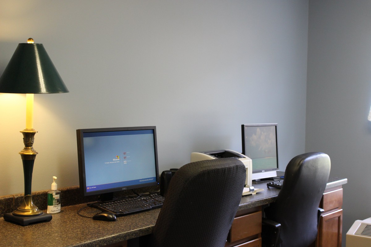 An office workspace featuring two computers on a desk with chairs.