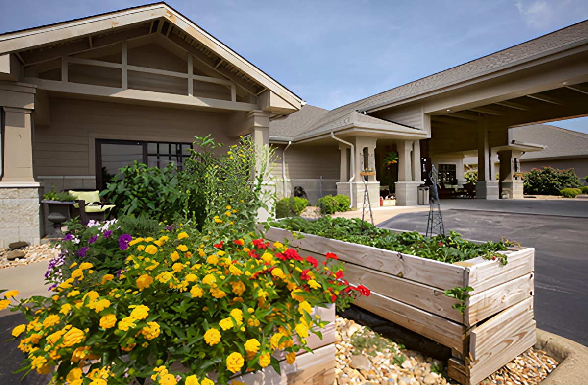 A beautiful garden with vibrant flowers and raised beds in front of a house.