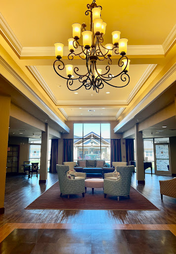 A beautifully designed lobby featuring elegant seating and a stunning chandelier, illuminated by ample natural light.