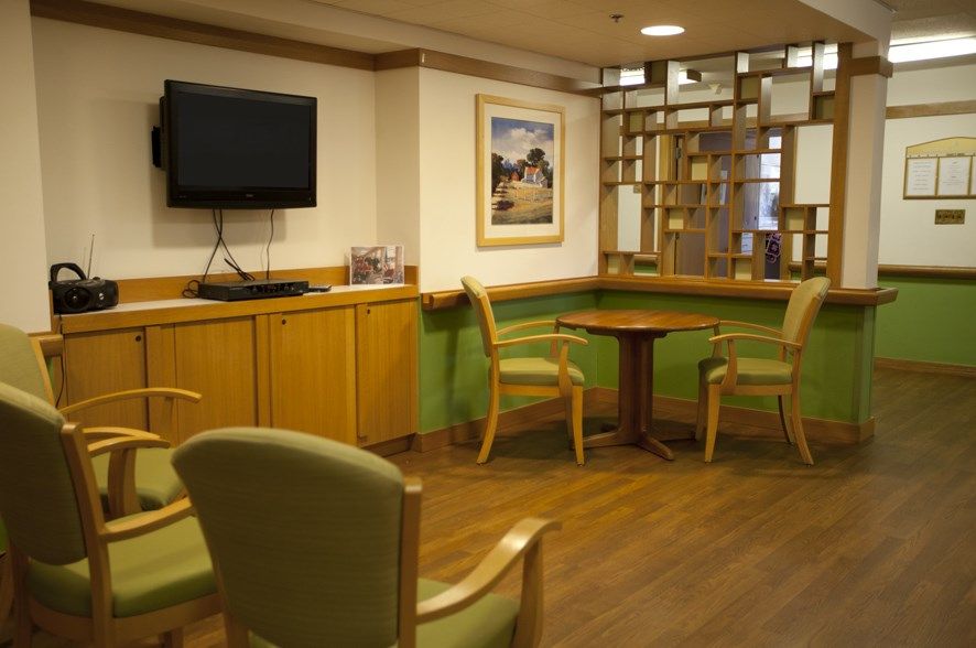 A cozy waiting room featuring comfortable chairs, a small table, and a television on the wall.